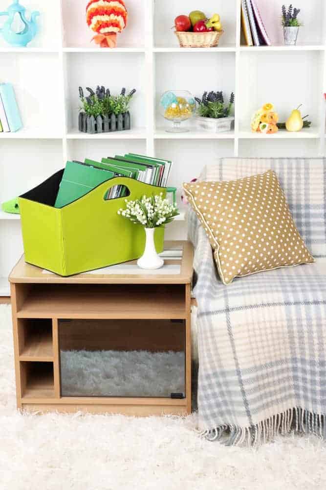 Magazines and folders in green box on bedside table in room in the organized home
